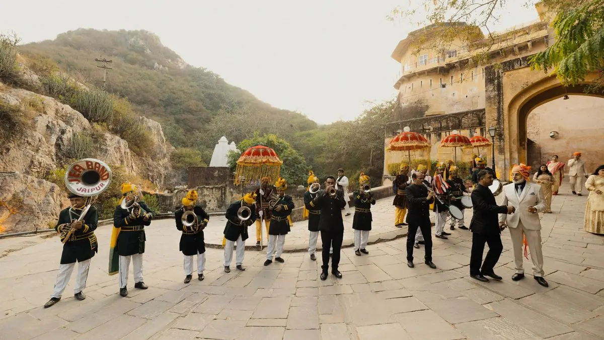 A brass band leading a wedding procession towards a venue gate
