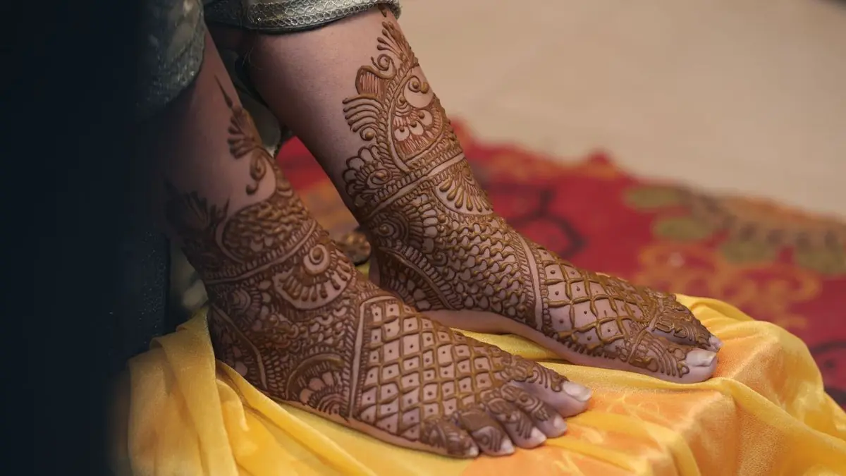 Bridal mehndi designs on a bride's feet resting on yellow fabric