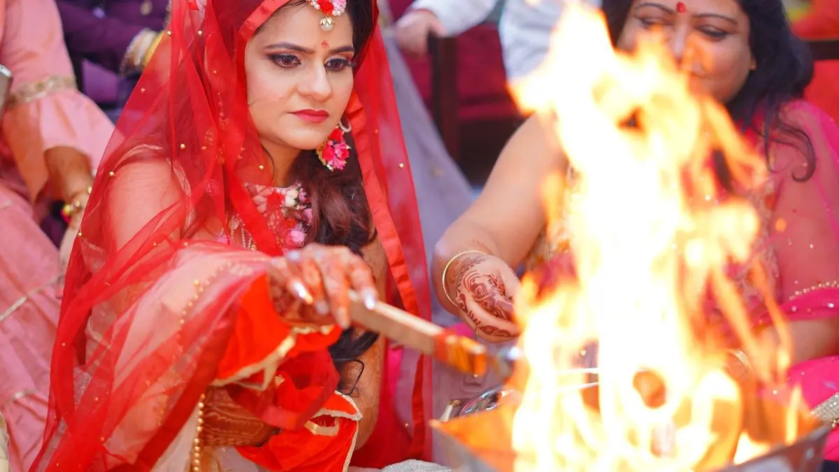 A bride making an offering into the sacred fire at a Hindu wedding