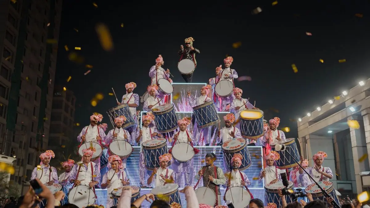 A troupe of dhol drummers performing at a wedding procession at night