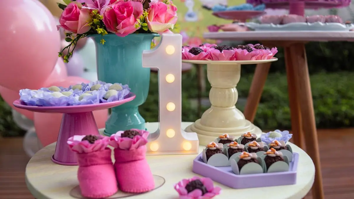 A first birthday dessert table with a light-up number one, flowers and sweets