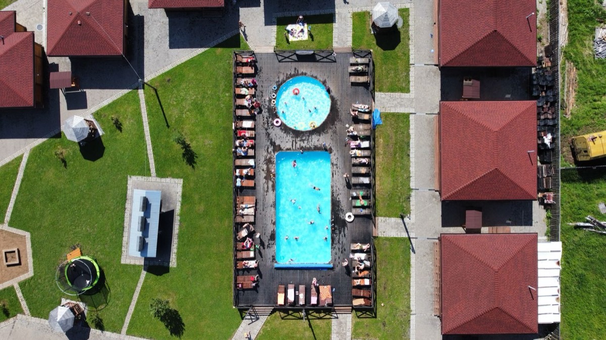 Aerial view of a resort with a pool, lawns and guest cottages