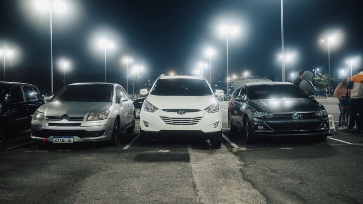 Cars parked in rows in a lit parking area at night