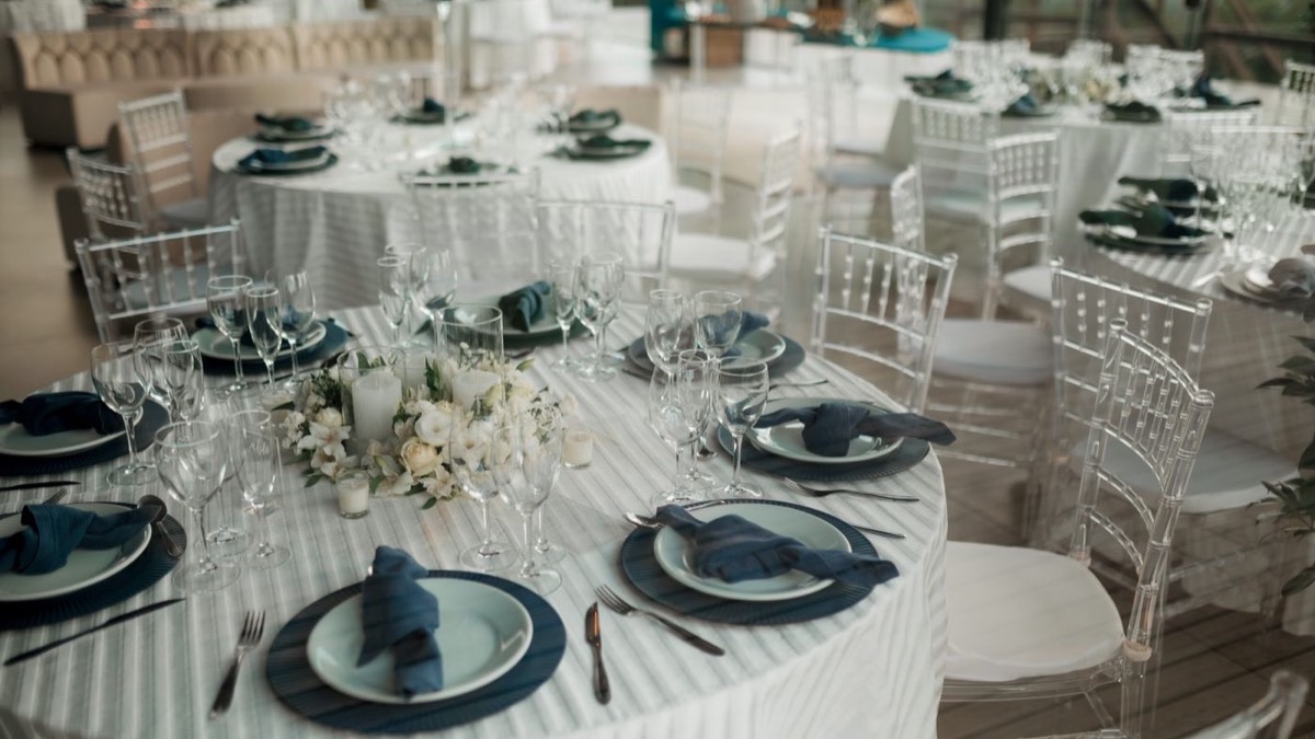 Round tables set for a wedding dinner with glassware and floral centrepieces